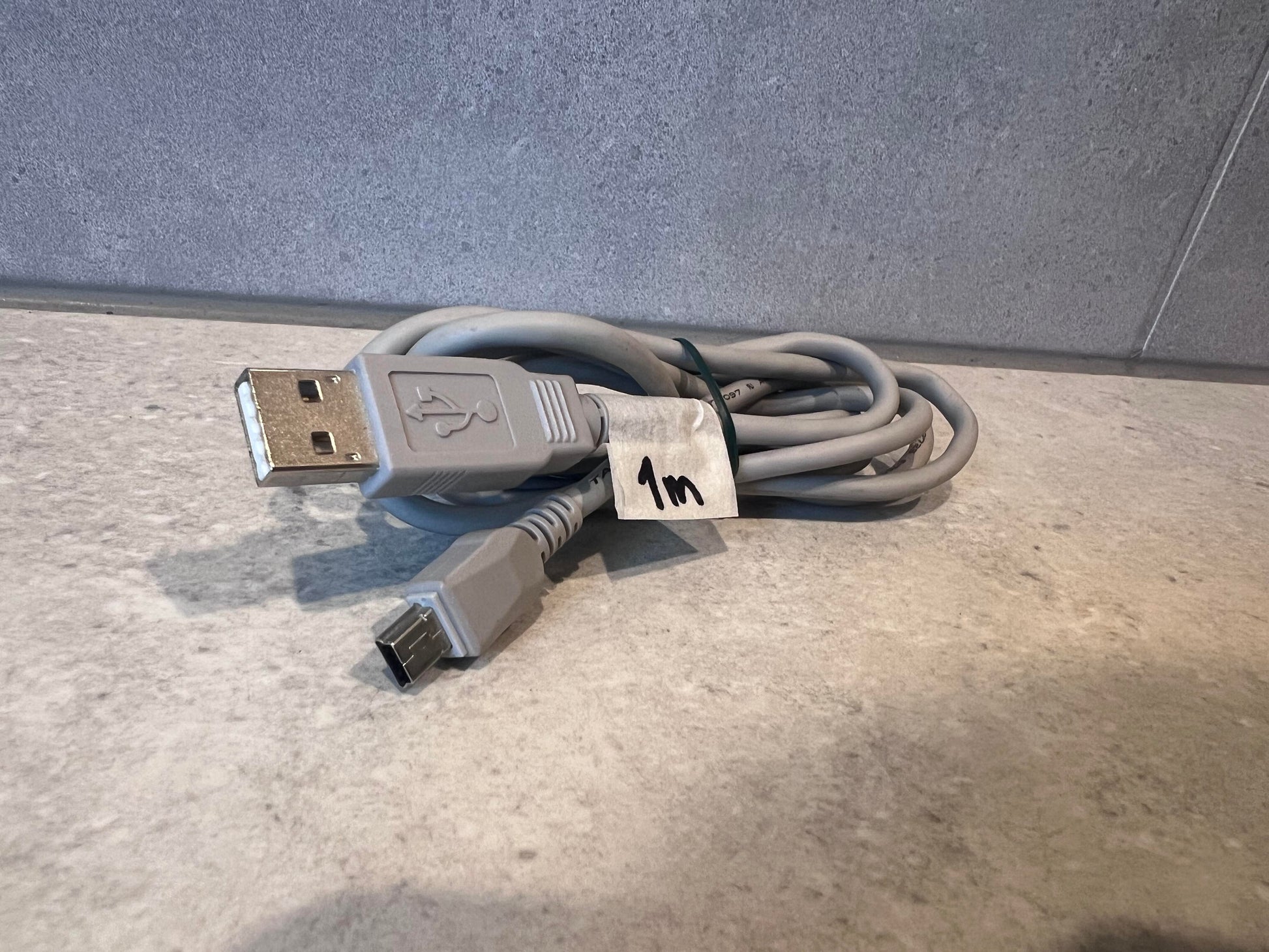 Coiled USB A to USB Mini-B cable on a light surface