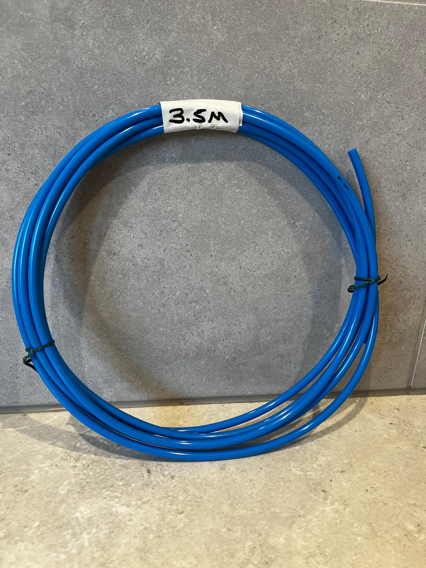Coiled 3.5-meter blue polyurethane tubing placed on a beige surface