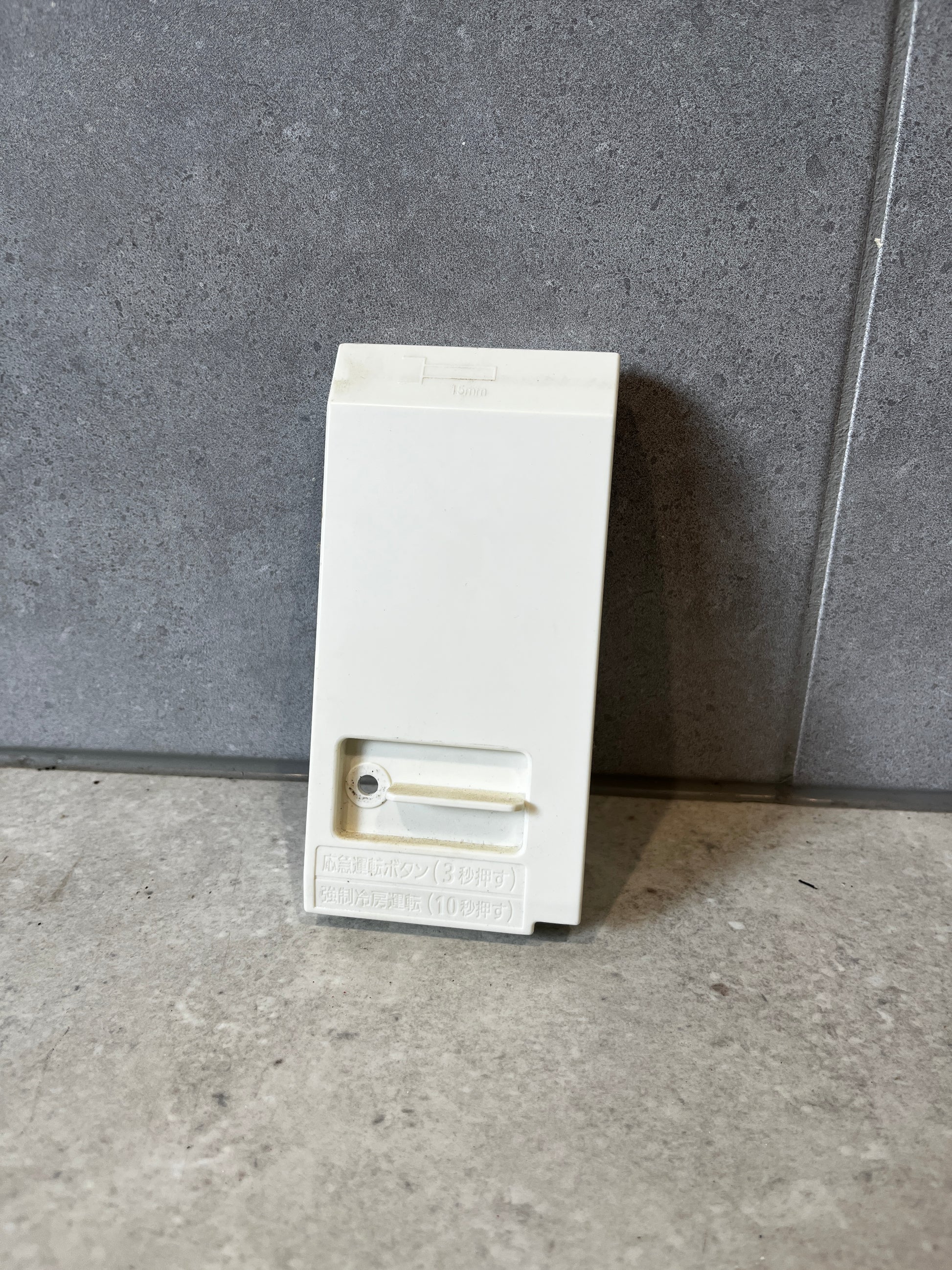 Front view of a white plastic electrical enclosure junction box on a gray surface