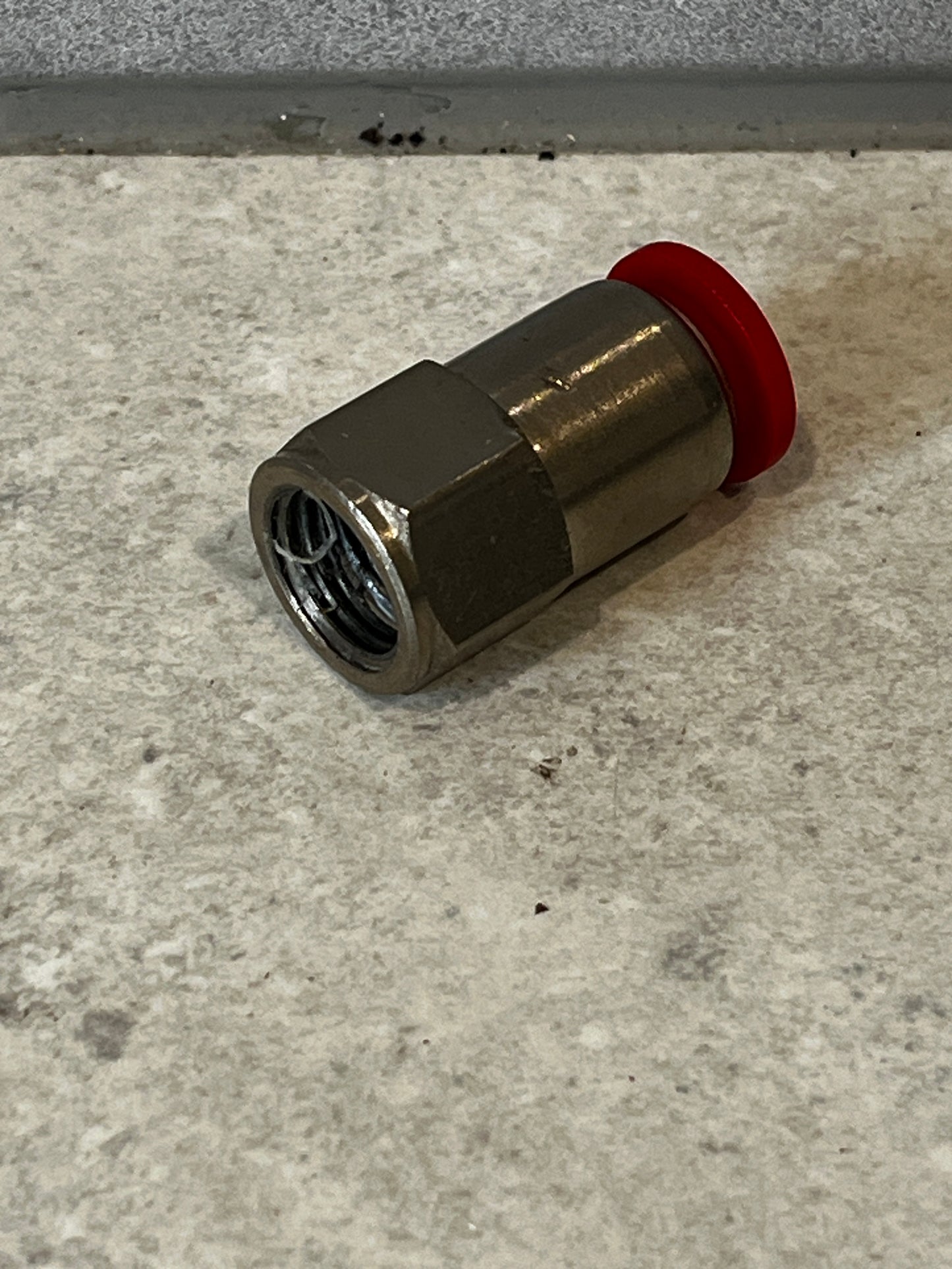 Coaxial cable compression connector with red compression ring lying on floor