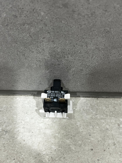 Front view of compact black push button switch mounted on white plastic base