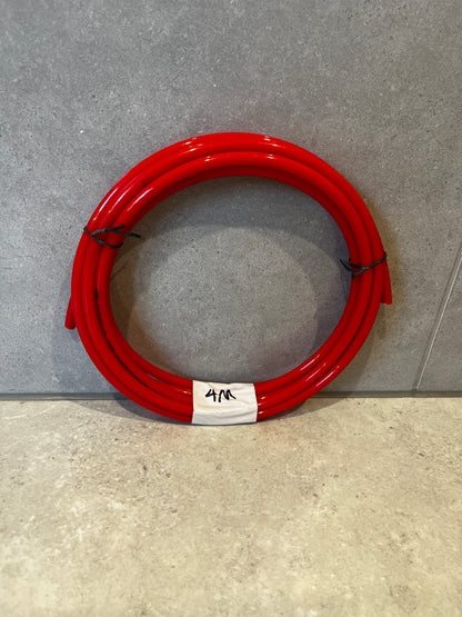 Coiled 4-meter red polyurethane tube on grey surface