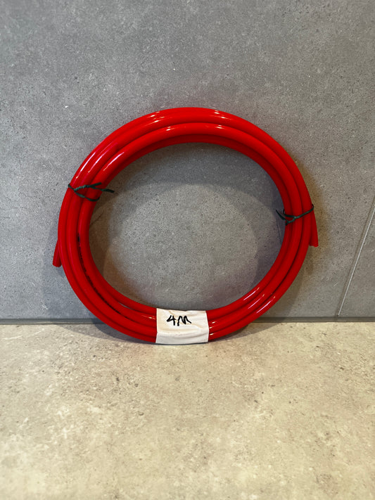 Coiled 4-meter red polyurethane tube on grey surface
