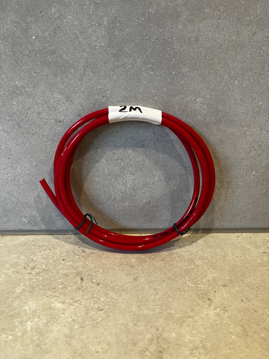 Coiled red polyurethane tubing labeled 2 meters on a grey surface