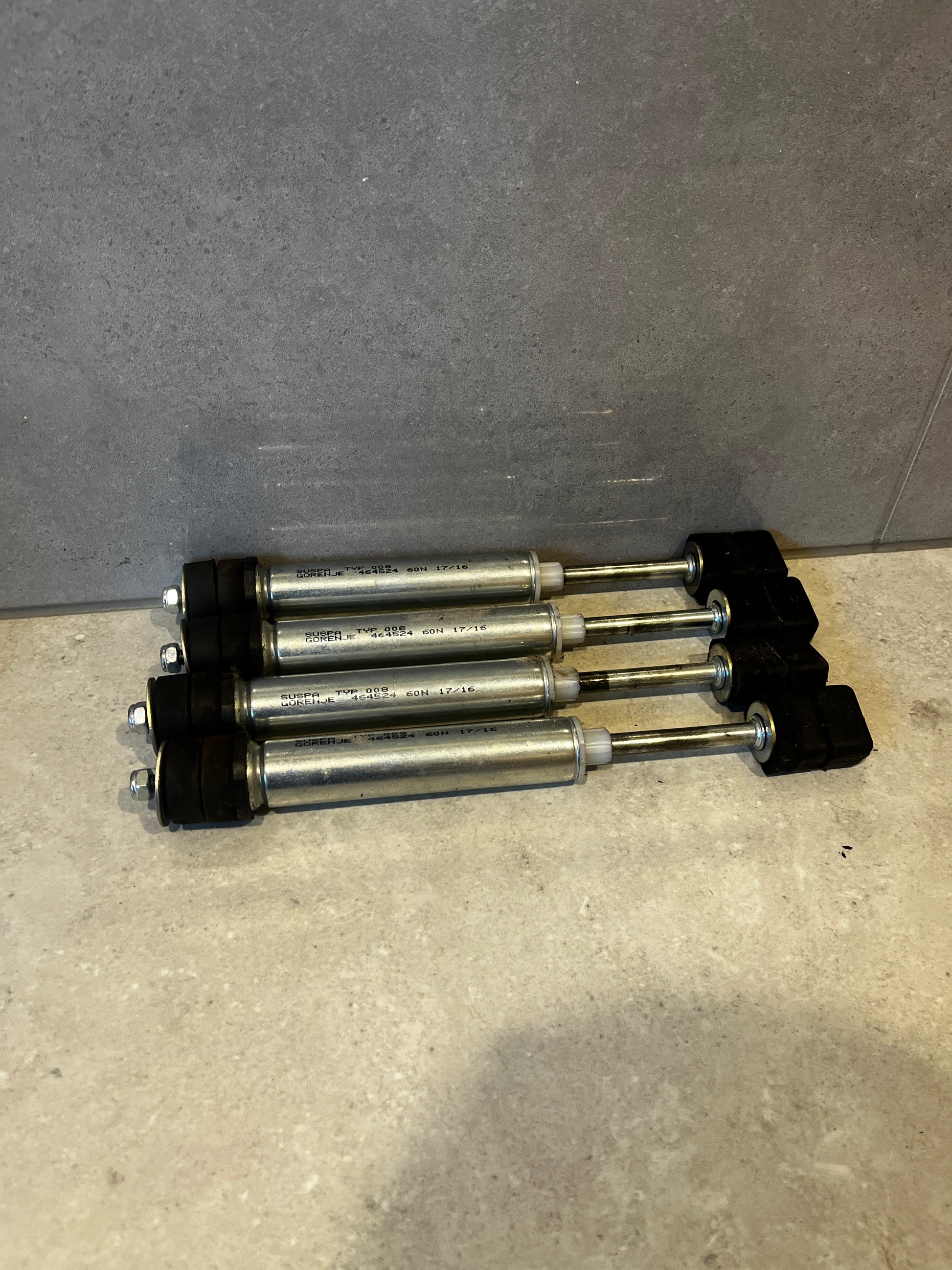 Four Gorenje SUSPA TYP 008 shock absorbers stacked on a surface