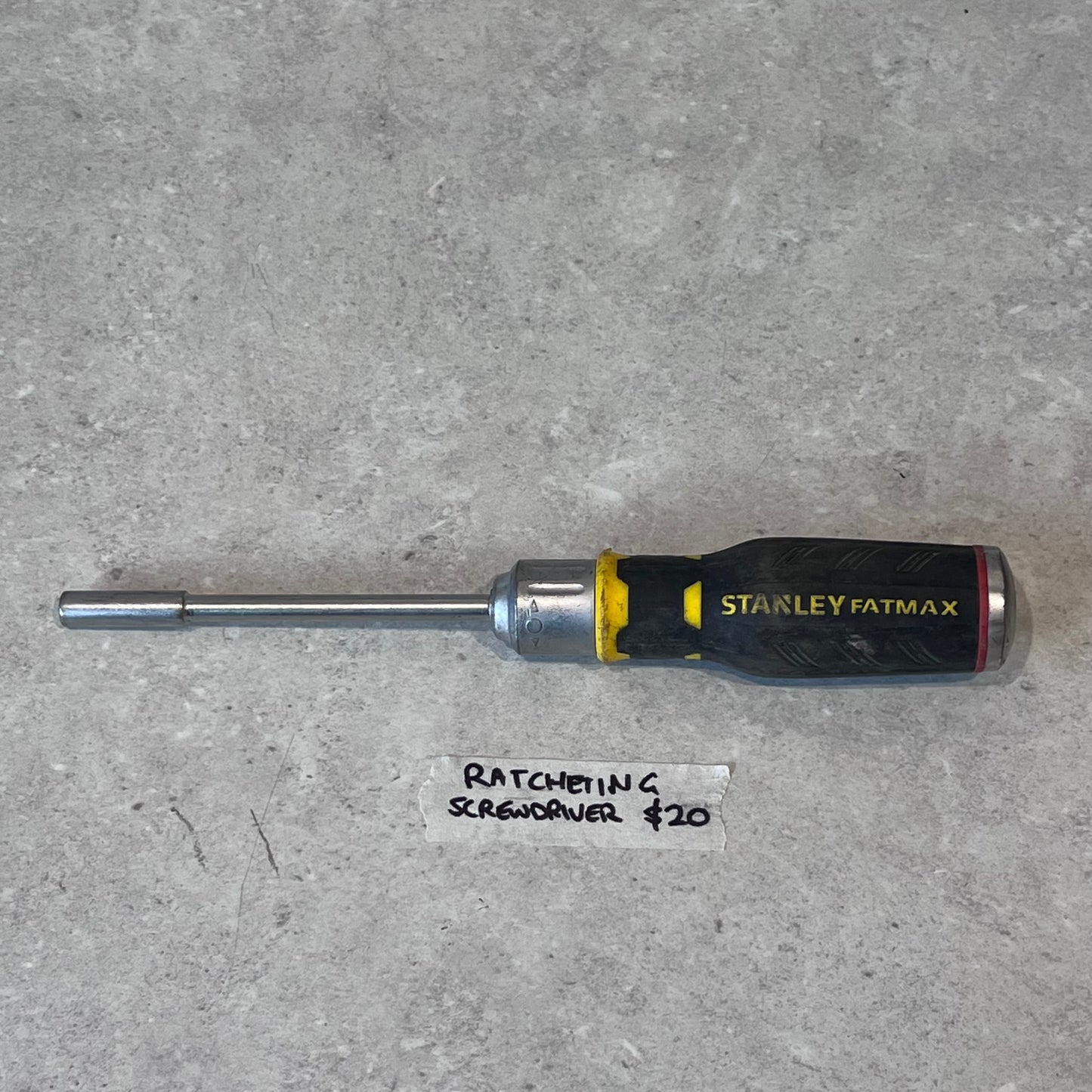 Stanley FatMax ratcheting screwdriver with black and yellow handle on gray surface