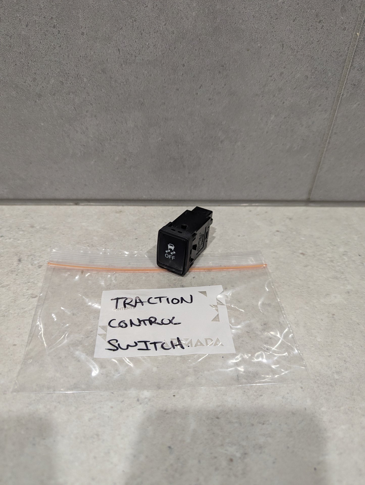 Traction control switch for automotive dashboards on countertop with labeled bag
