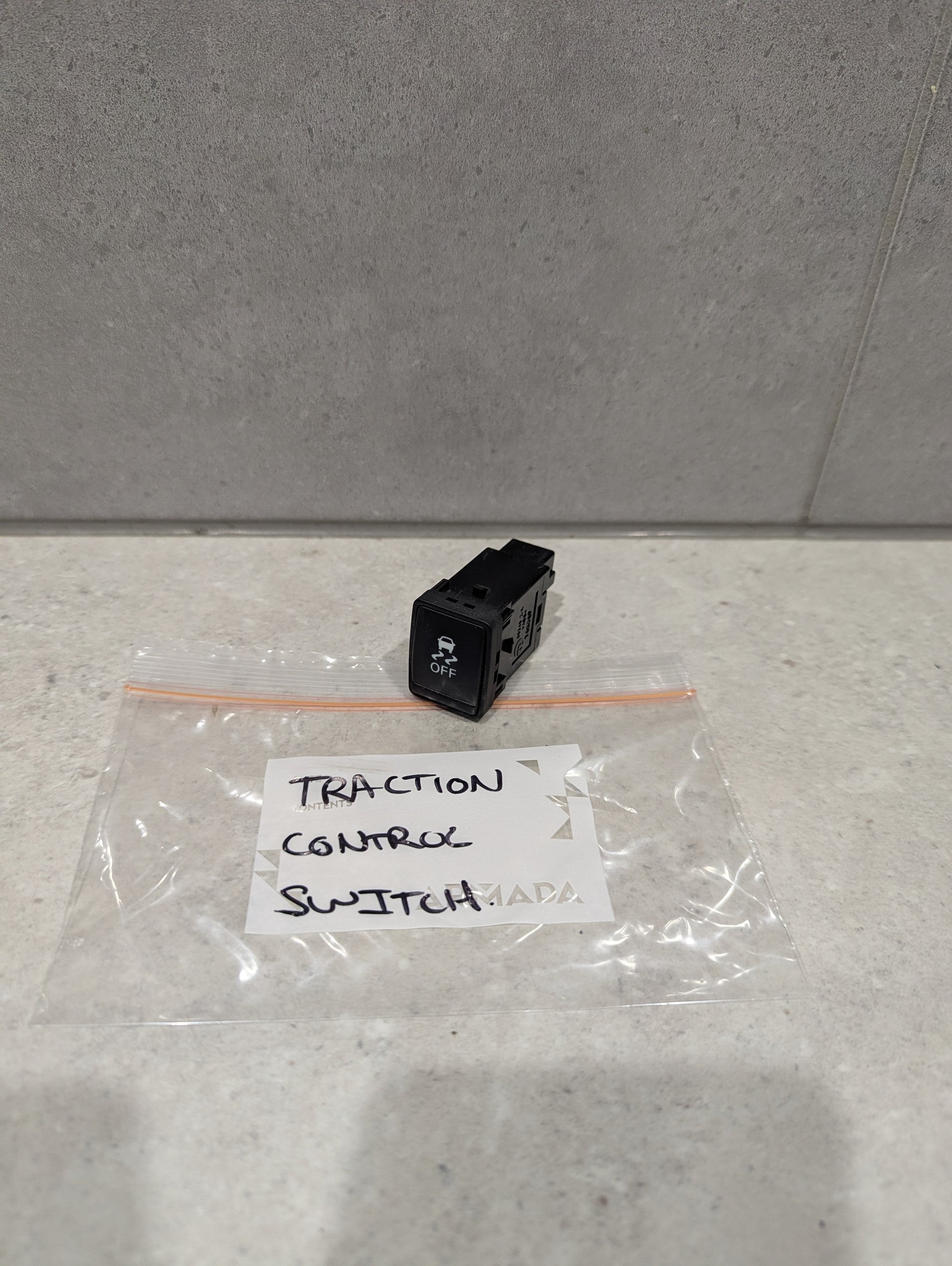 Traction control switch for automotive dashboards on countertop with labeled bag