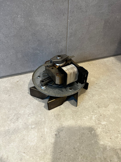 Electric fan motor assembly with metal base and coil wrapped in white insulation