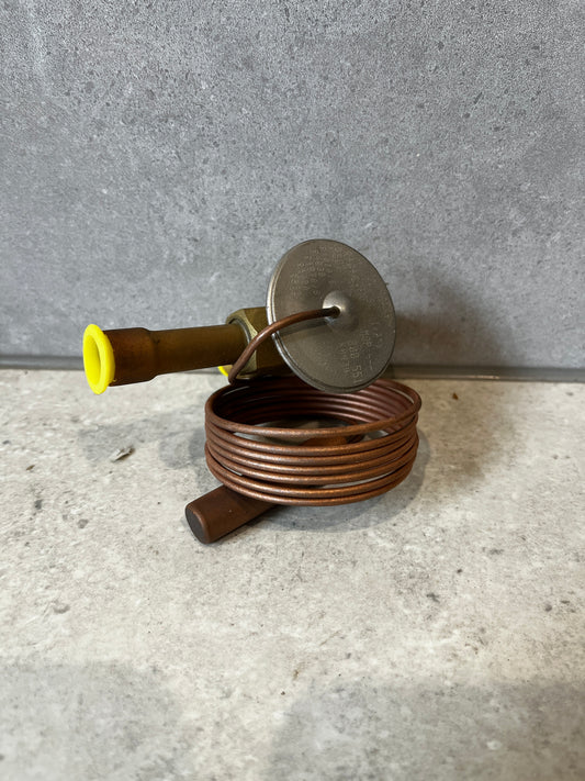 Copper capillary thermostatic expansion valve with brass fittings shown on grey background