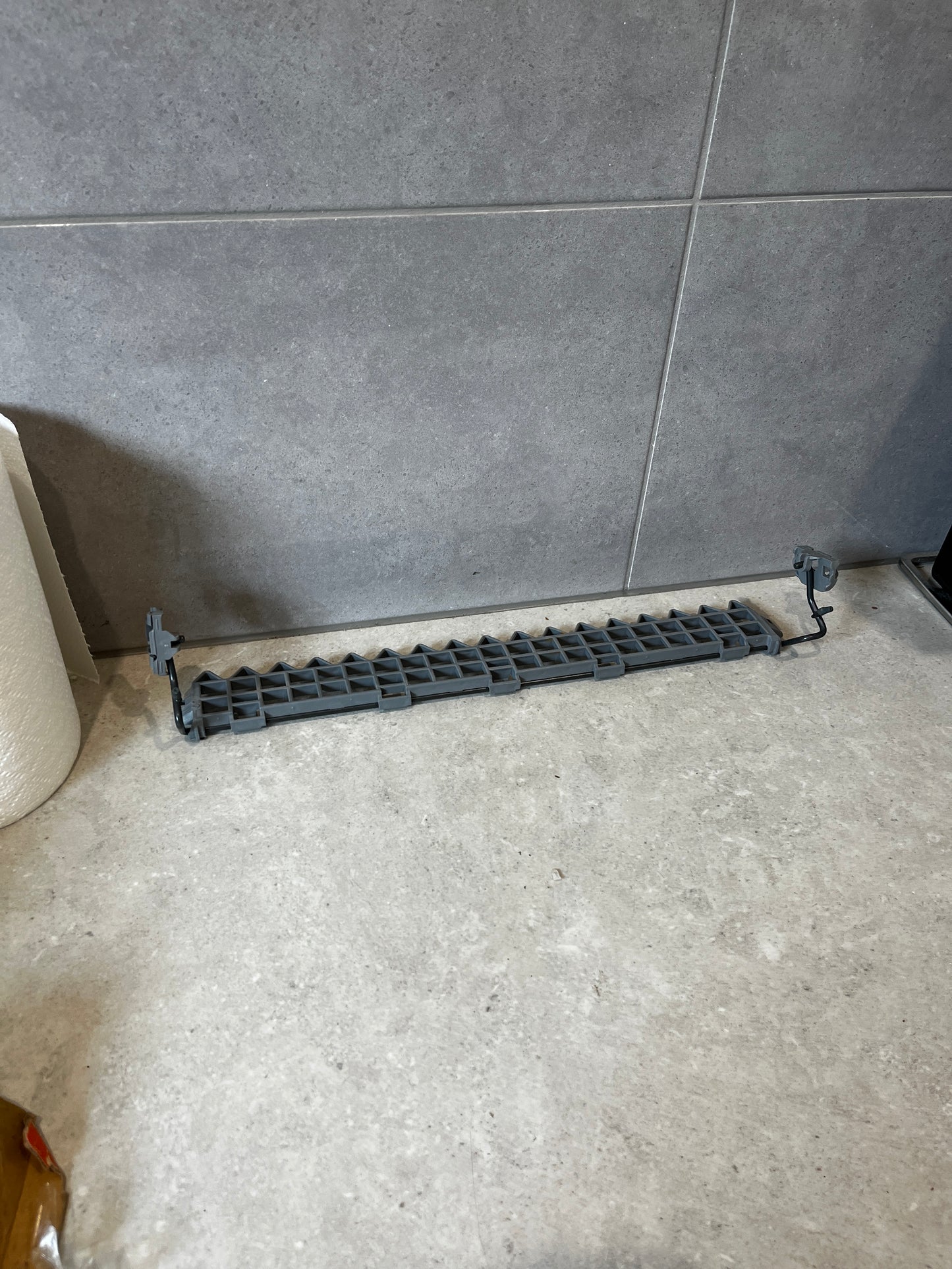 Gray plastic dishwasher basket rack with locking tabs on a kitchen counter