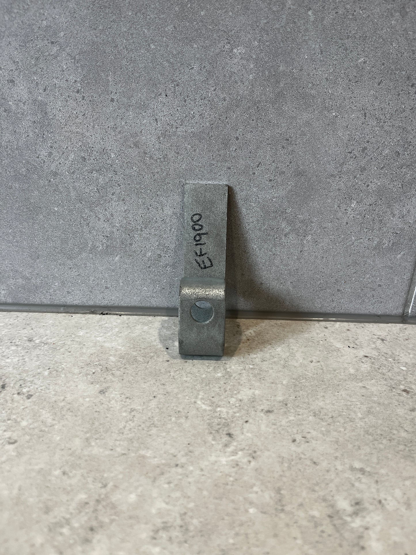 Heavy-duty steel mounting bracket standing upright on a gray stone surface