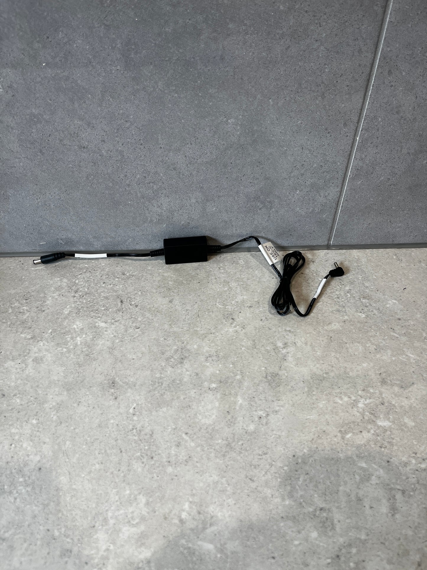 Black DC power adapter cable for TEC-C base shown on gray surface