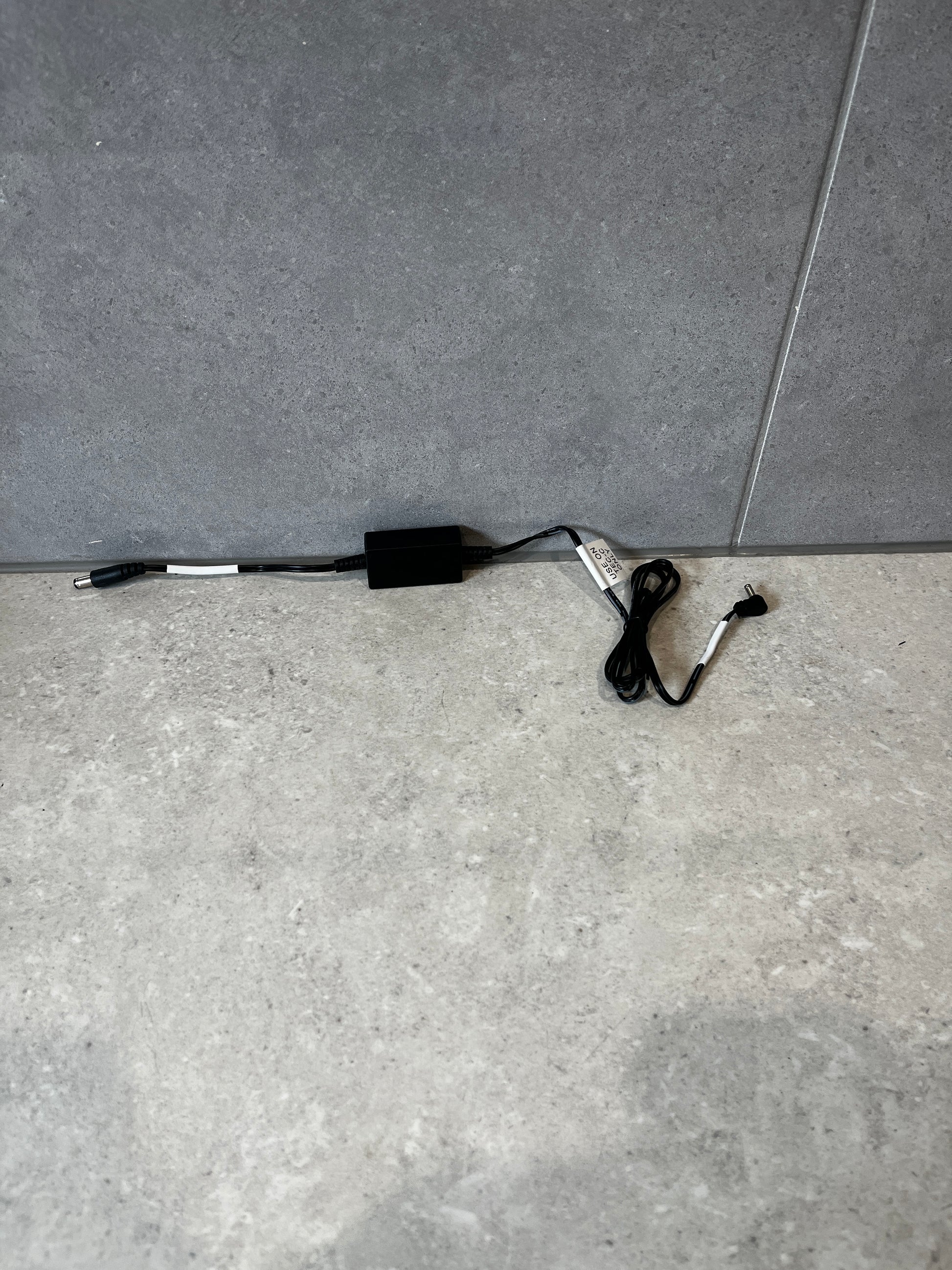 Black DC power adapter cable for TEC-C base shown on gray surface
