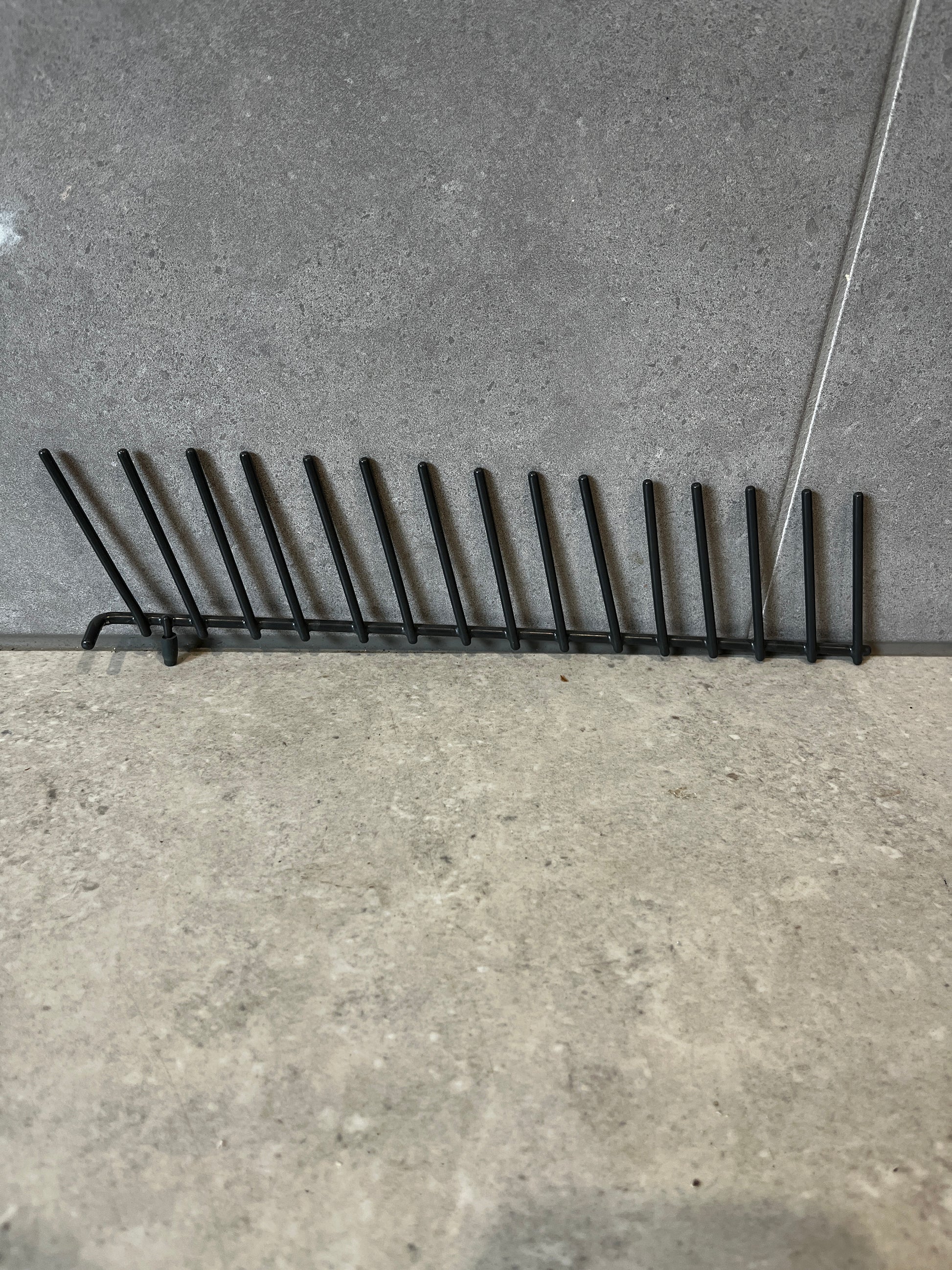 Black metal vertical plate rack on gray tile surface