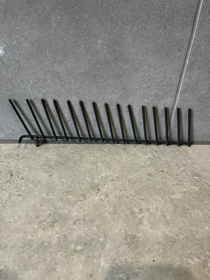 Black metal vertical plate rack on gray tile surface