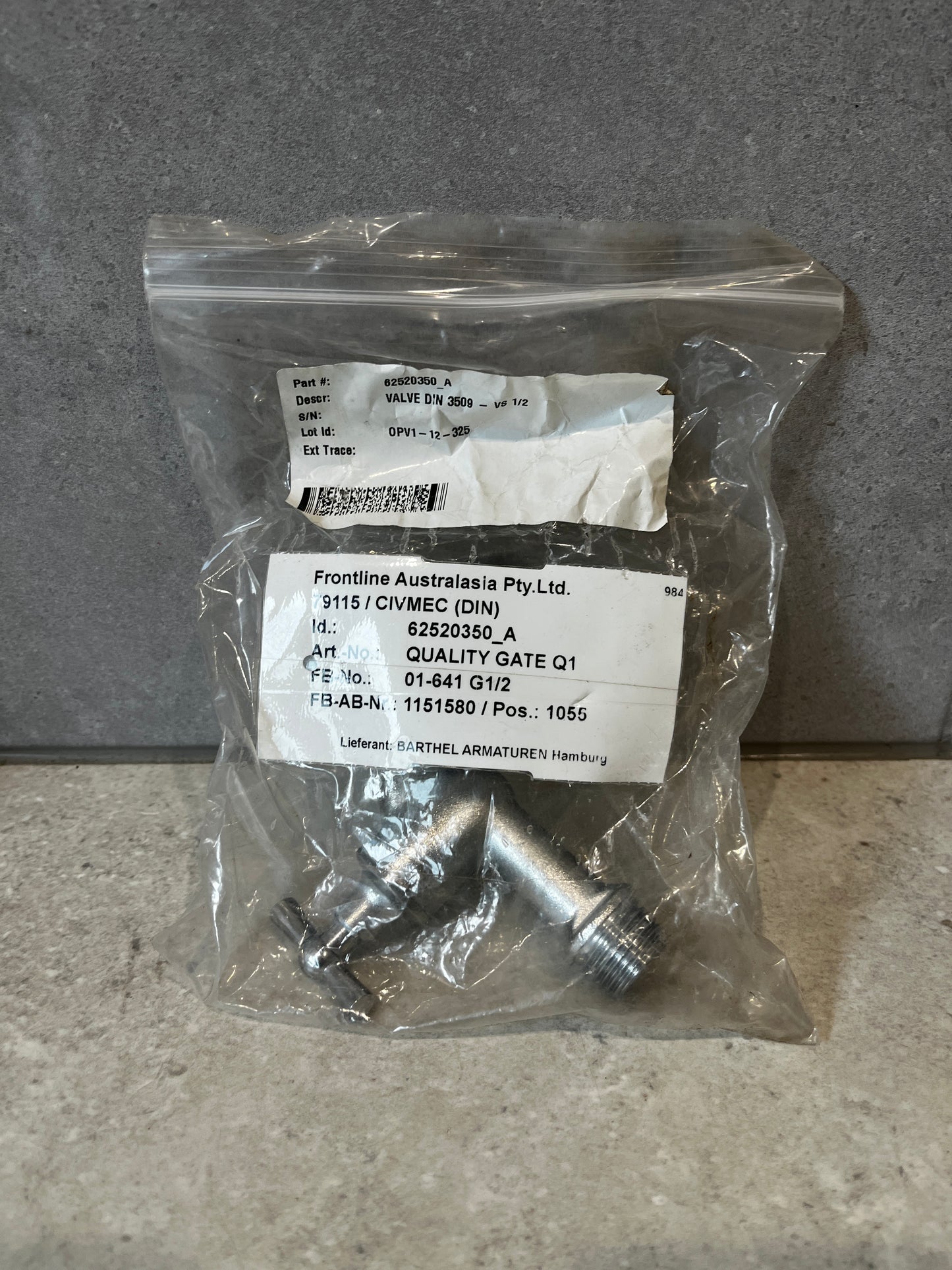 Stainless steel outdoor water tap in original packaging on a stone surface