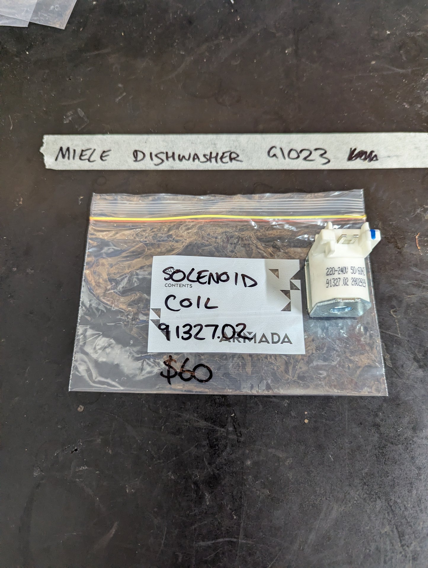 Miele dishwasher G1023 solenoid coil in labeled plastic bag on dark surface