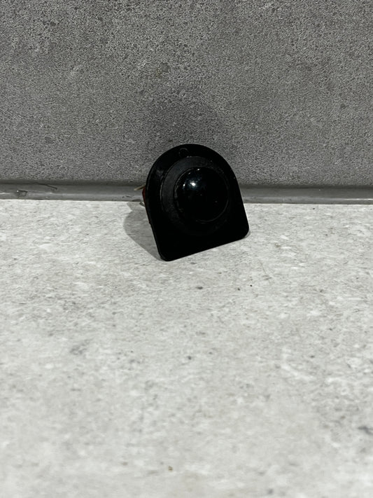 Front view of black round rocker switch on gray surface