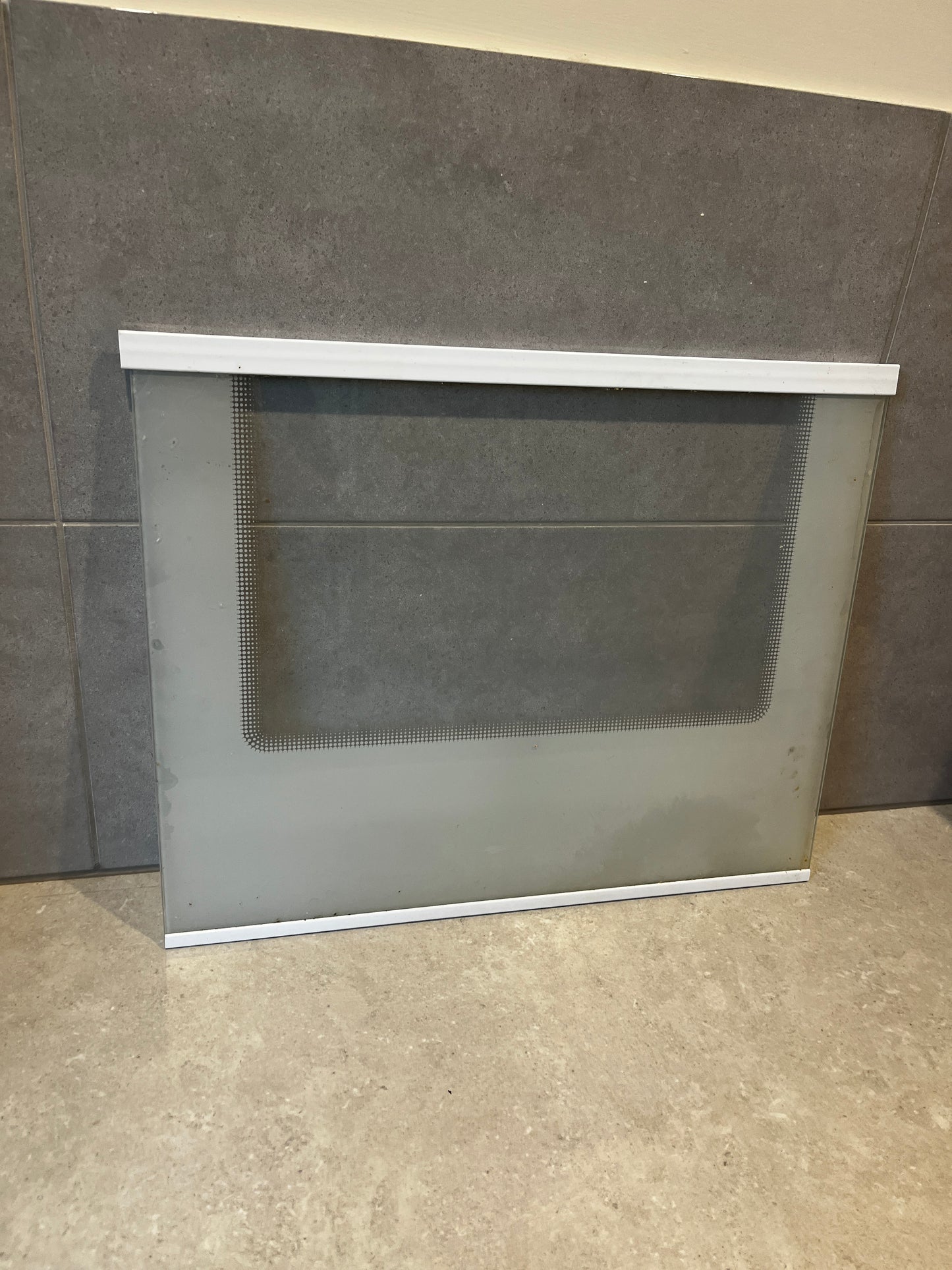 Fridge Glass  panel with white frame resting against tiled wall
