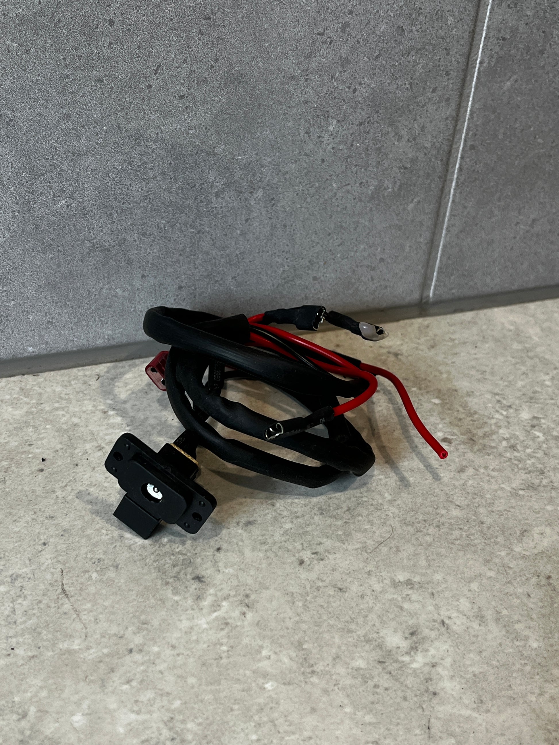 Universal power outlet socket with attached wiring harness on gray surface