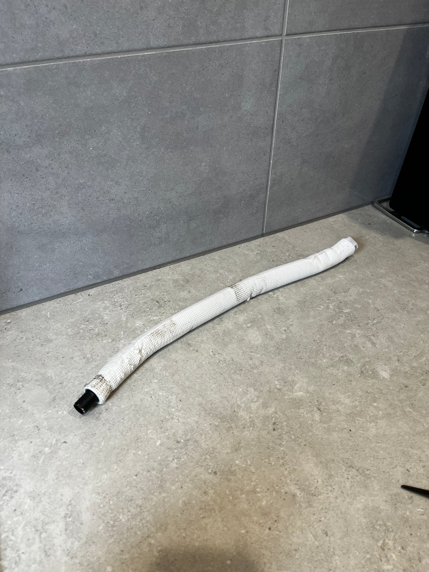 Flexible automotive fuel hose with protective white sleeve on a countertop