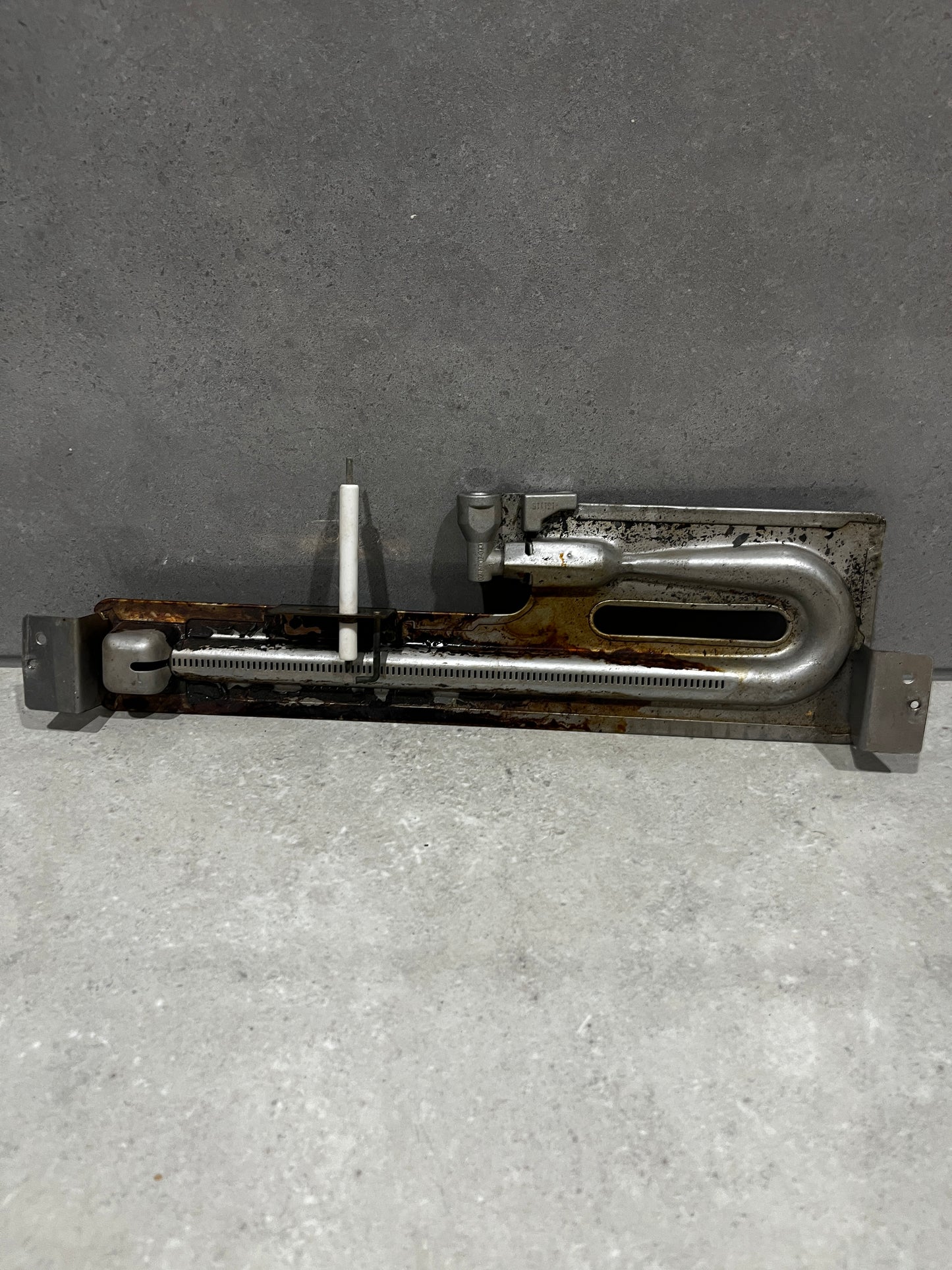 Metal oven burner assembly with attached ceramic ignition electrode and mounting brackets