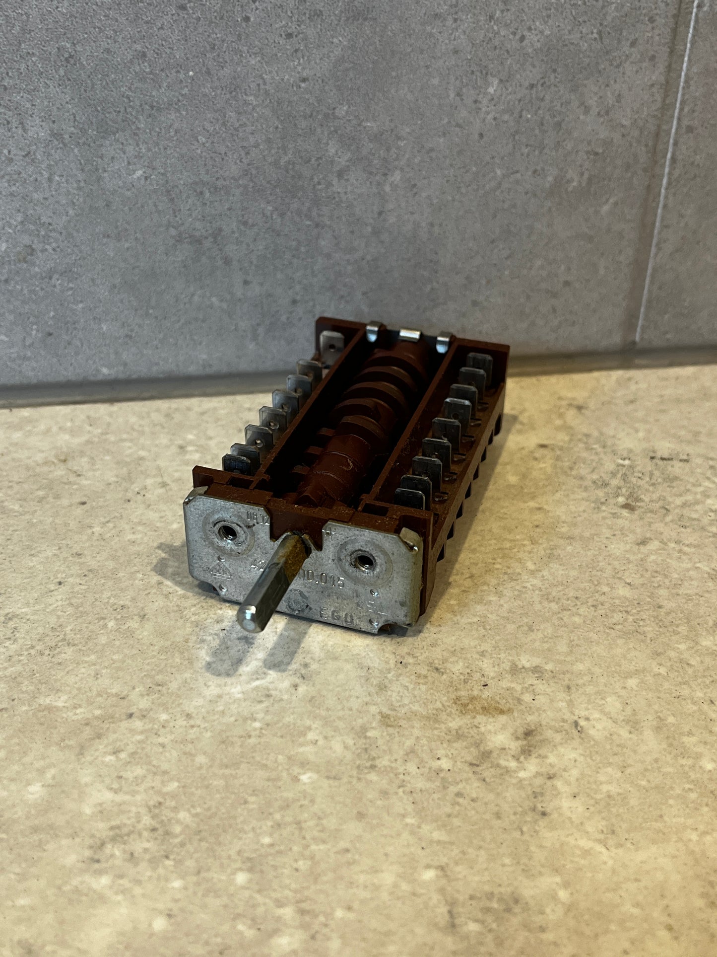 Rotary switch component with brown plastic casing and metal shaft on light surface