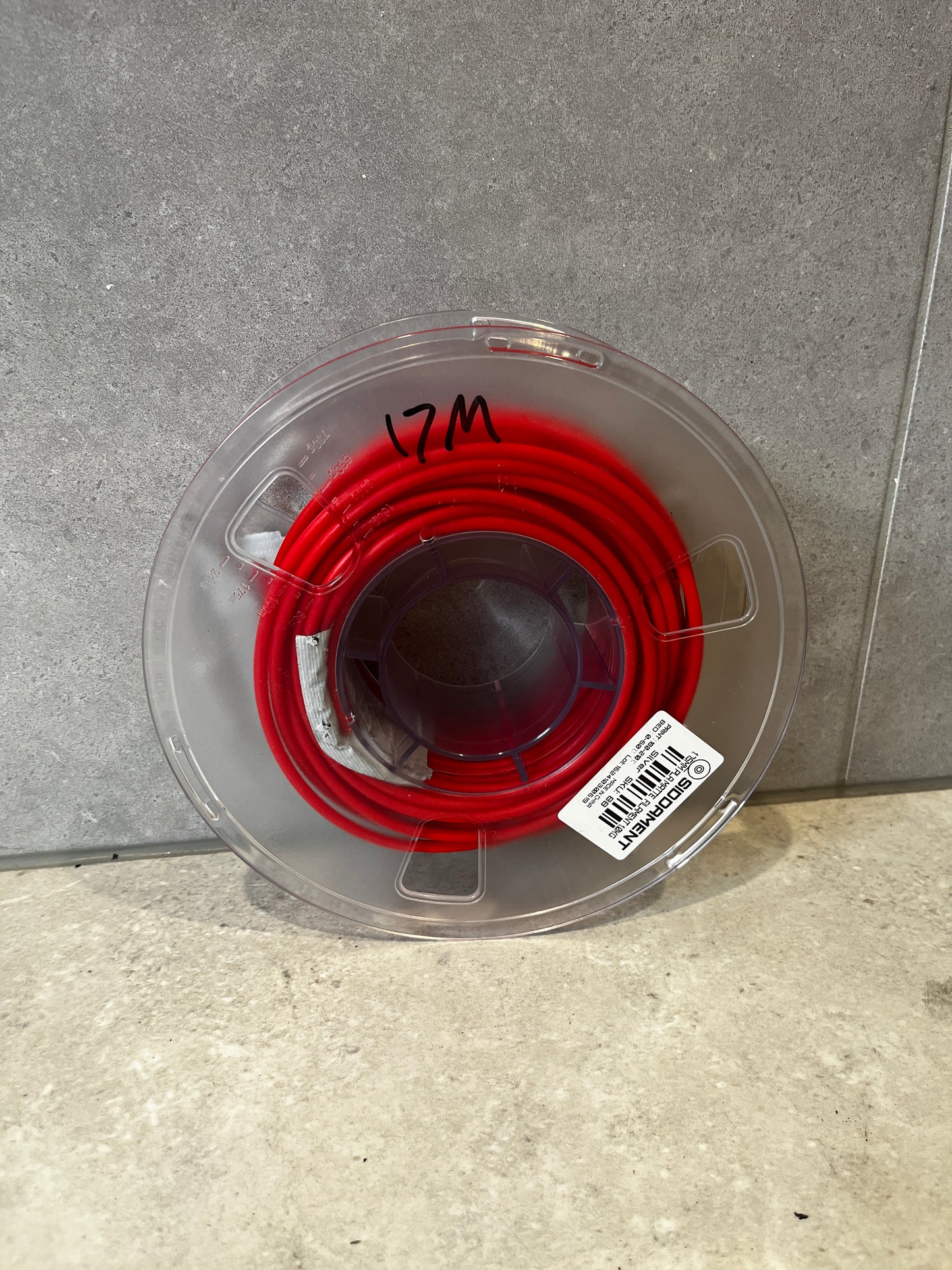 Top view of red polyethylene tubing on a clear plastic spool