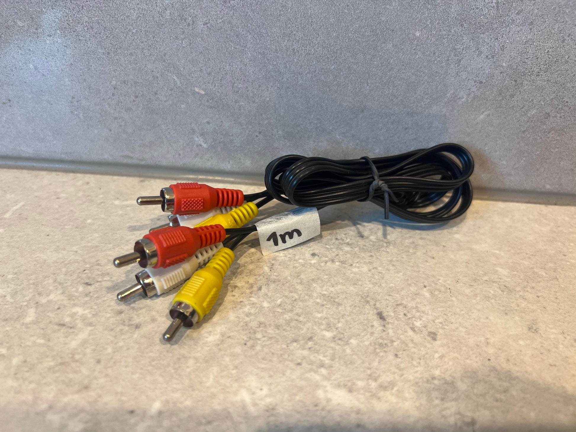 Three-color RCA composite audio video cable coiled on a light surface