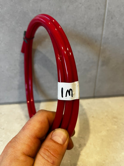 Close-up of hand holding red polyurethane tubing coil labeled 1 meter