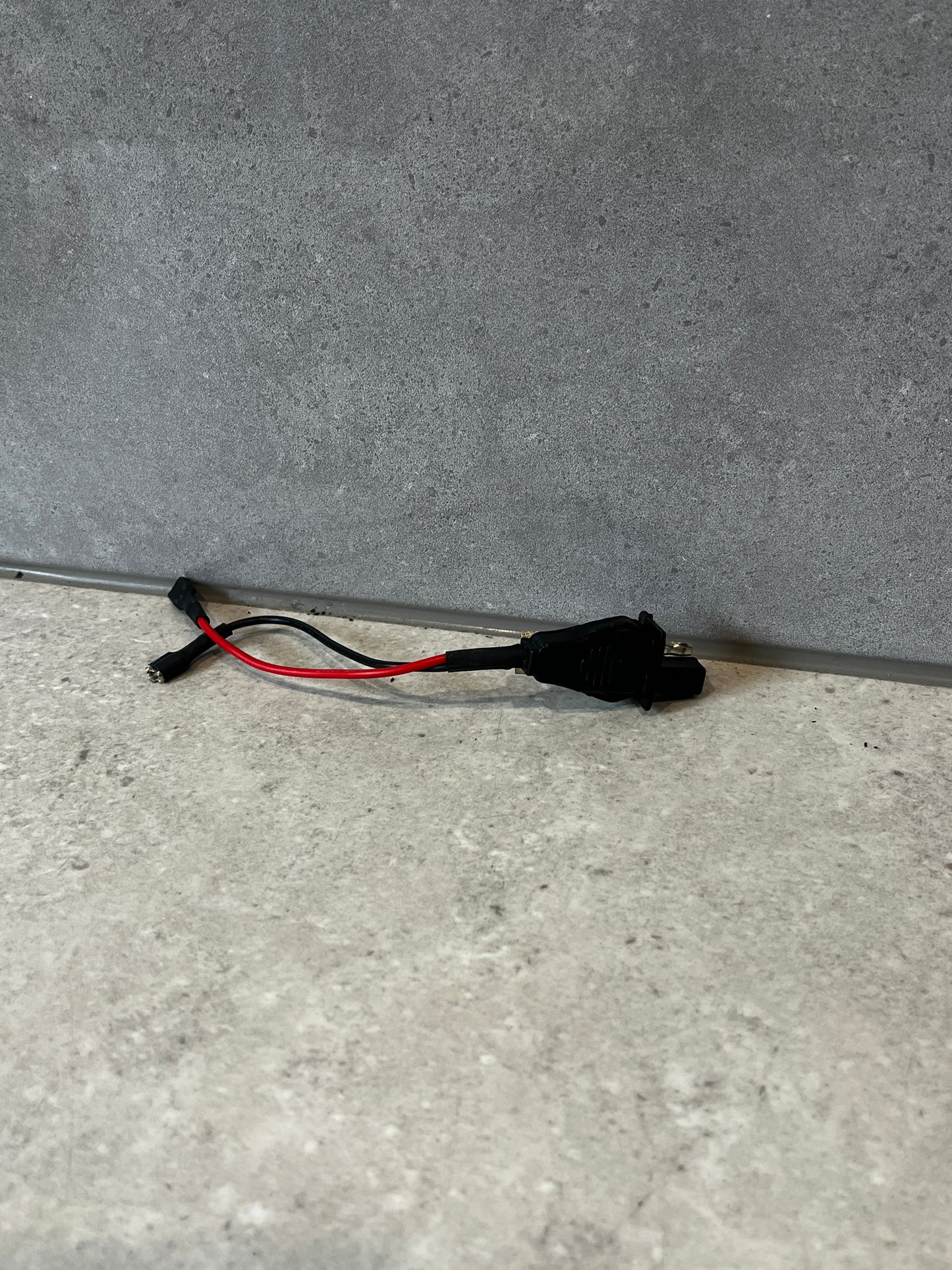 Automotive power adapter harness with black connectors and red-black wires on a gray surface