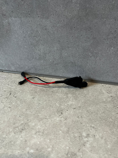 Automotive power adapter harness with black connectors and red-black wires on a gray surface