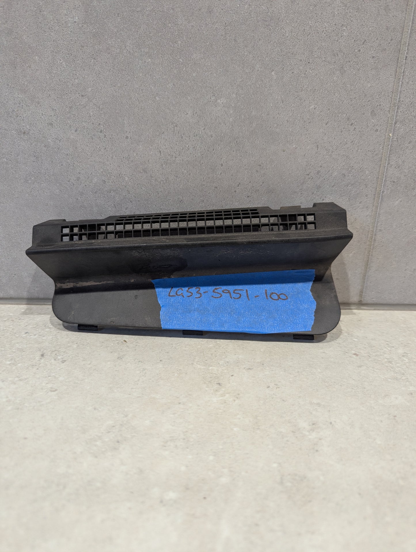 Black plastic vent grille component on a light surface