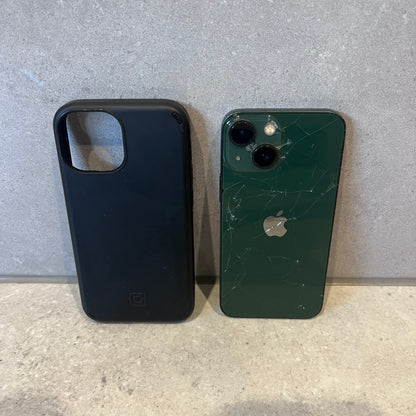 Cracked green iPhone 13 Mini next to black phone case on stone surface