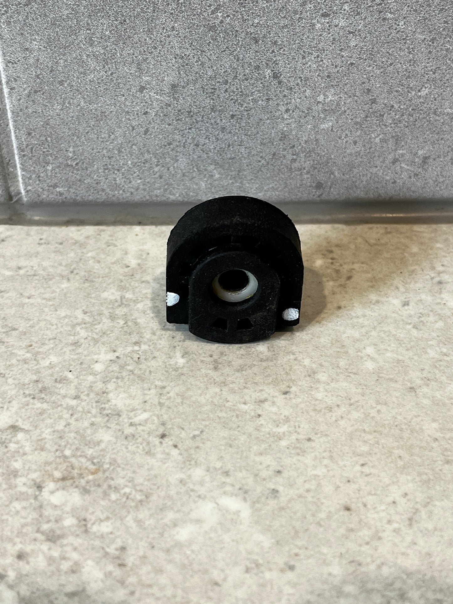 Heavy-duty rubber bushing mount with metal sleeve on stone surface