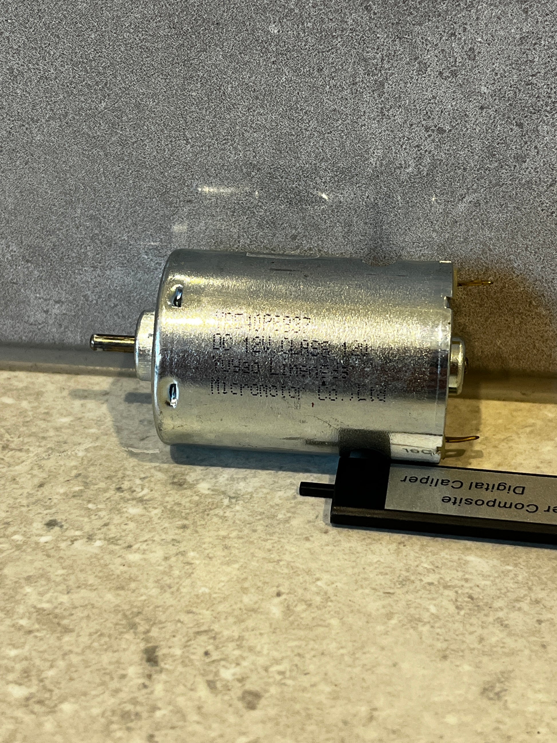 Side view of a small cylindrical electric DC motor with metal housing and output shaft