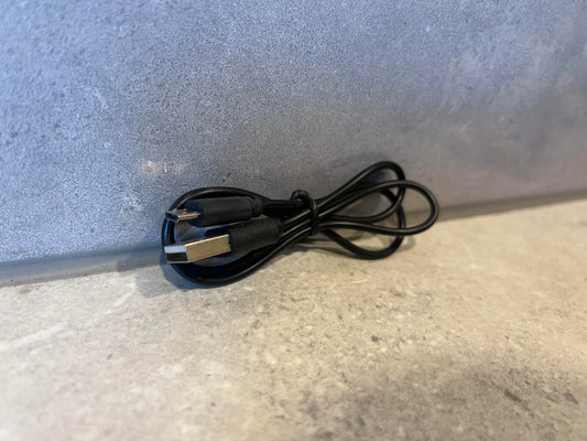 Coiled USB-A to USB-C black charging cable on a stone surface
