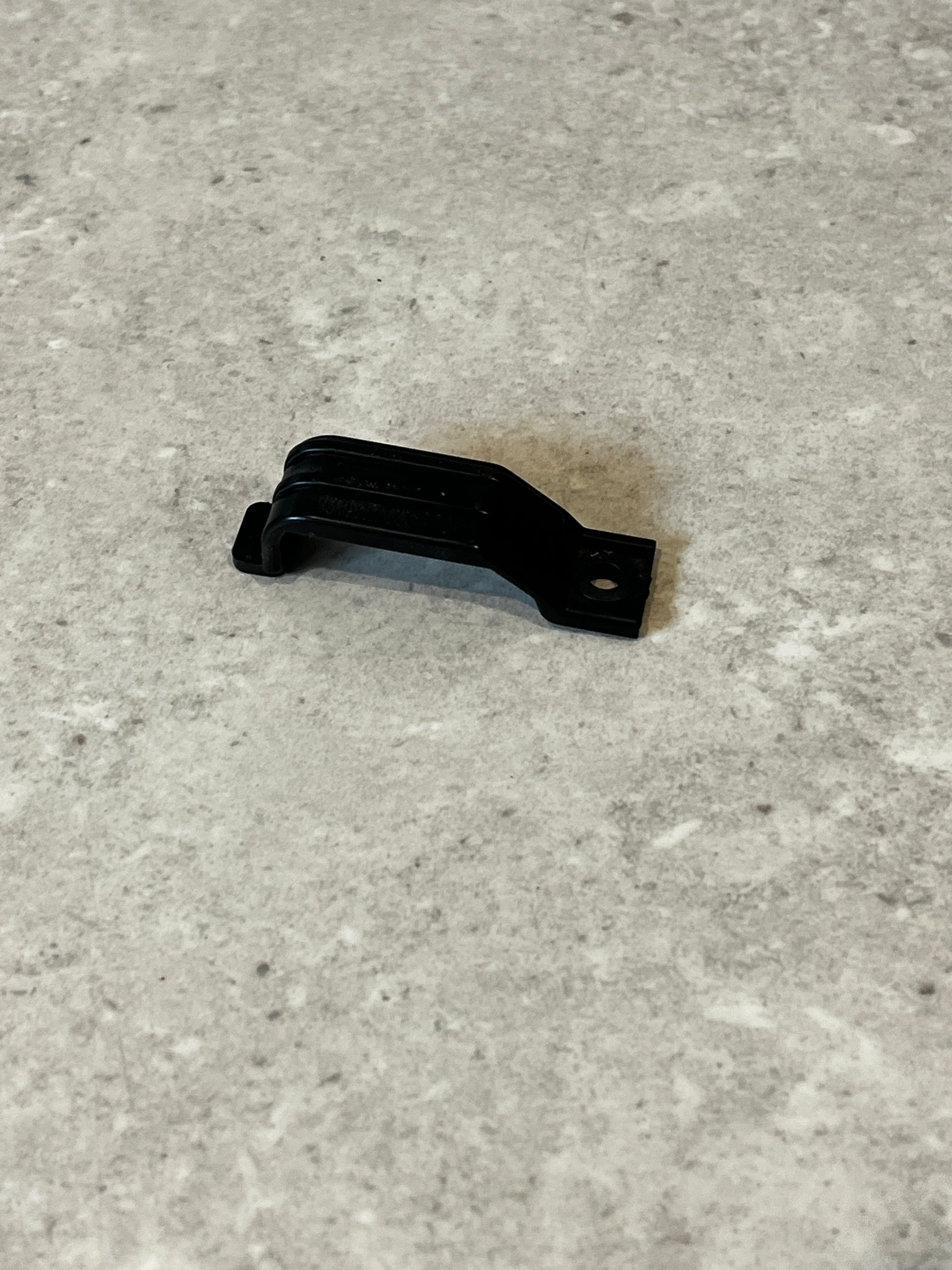 Black plastic mounting bracket clip on gray surface