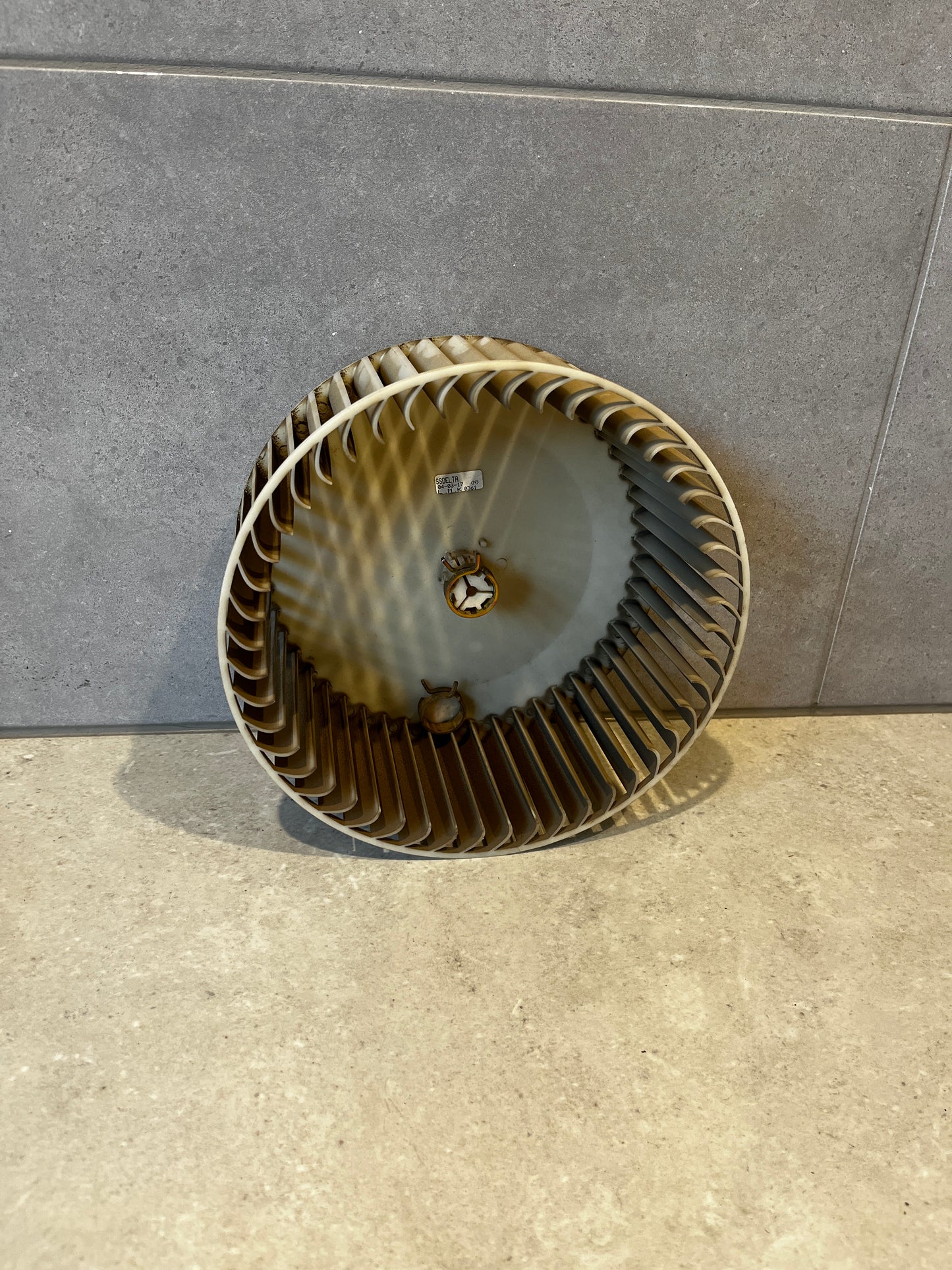 Round HVAC blower wheel fan with multiple blades against tiled background