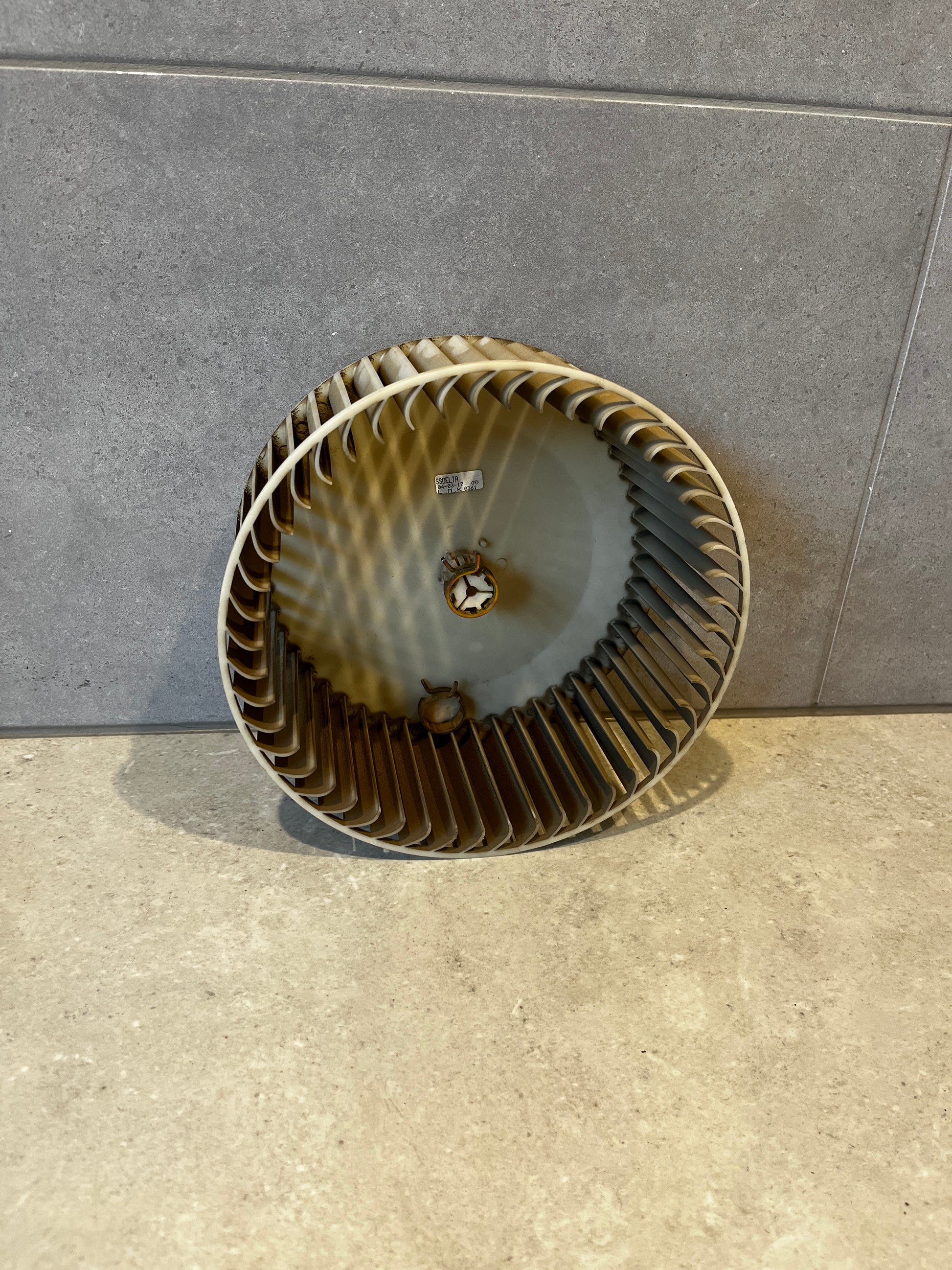 Round HVAC blower wheel fan with multiple blades against tiled background