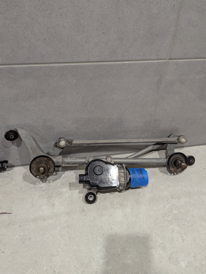 Full view of automotive wiper linkage and motor assembly on a gray surface