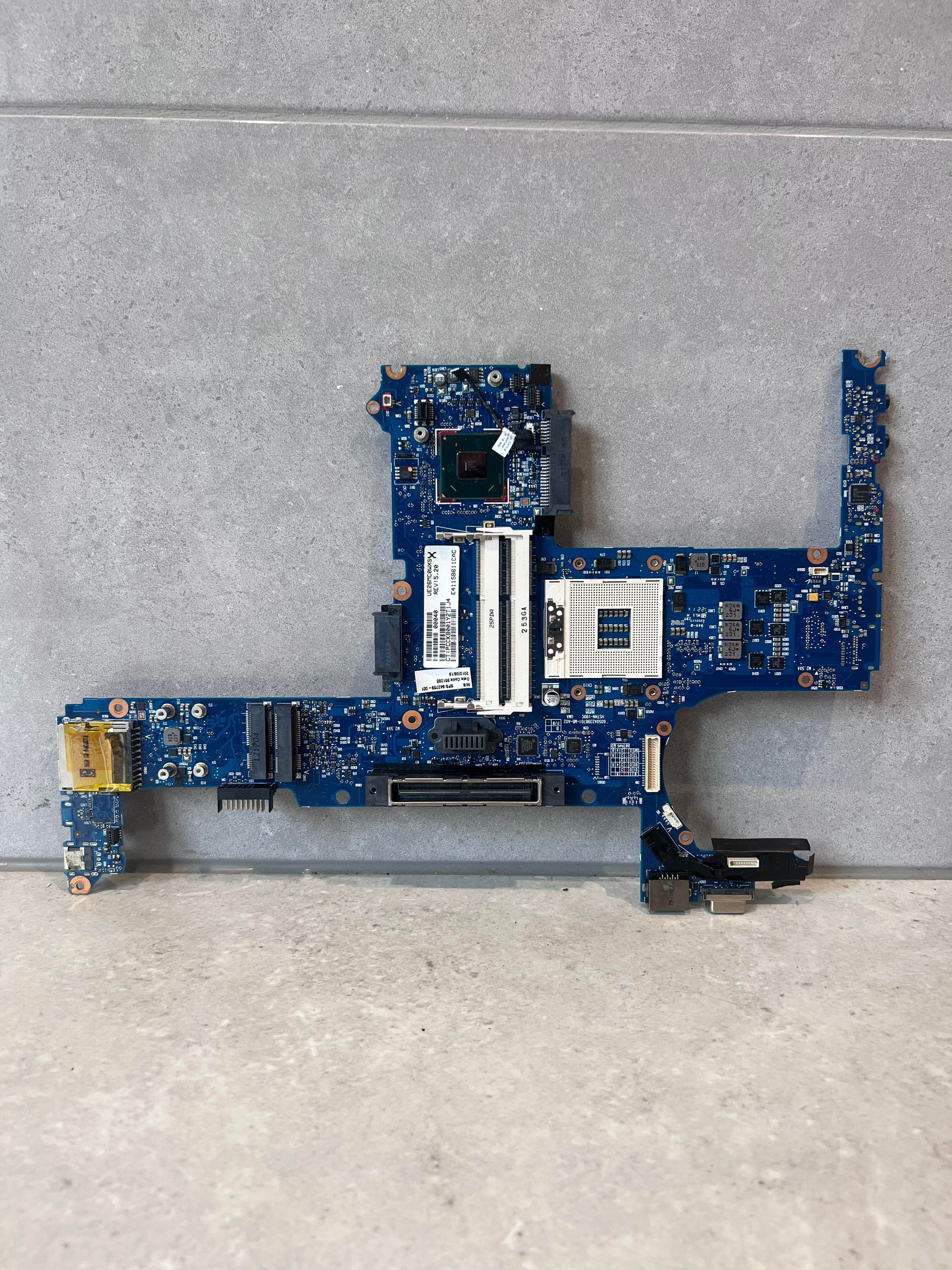 Front view of a blue laptop mainboard replacement part on a gray surface