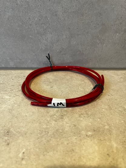 Coiled red pneumatic tubing on a beige surface