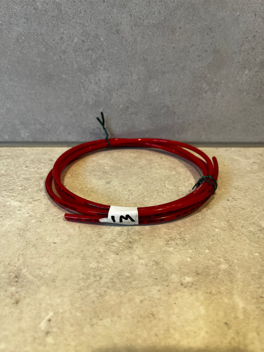 Coiled red pneumatic tubing on a beige surface