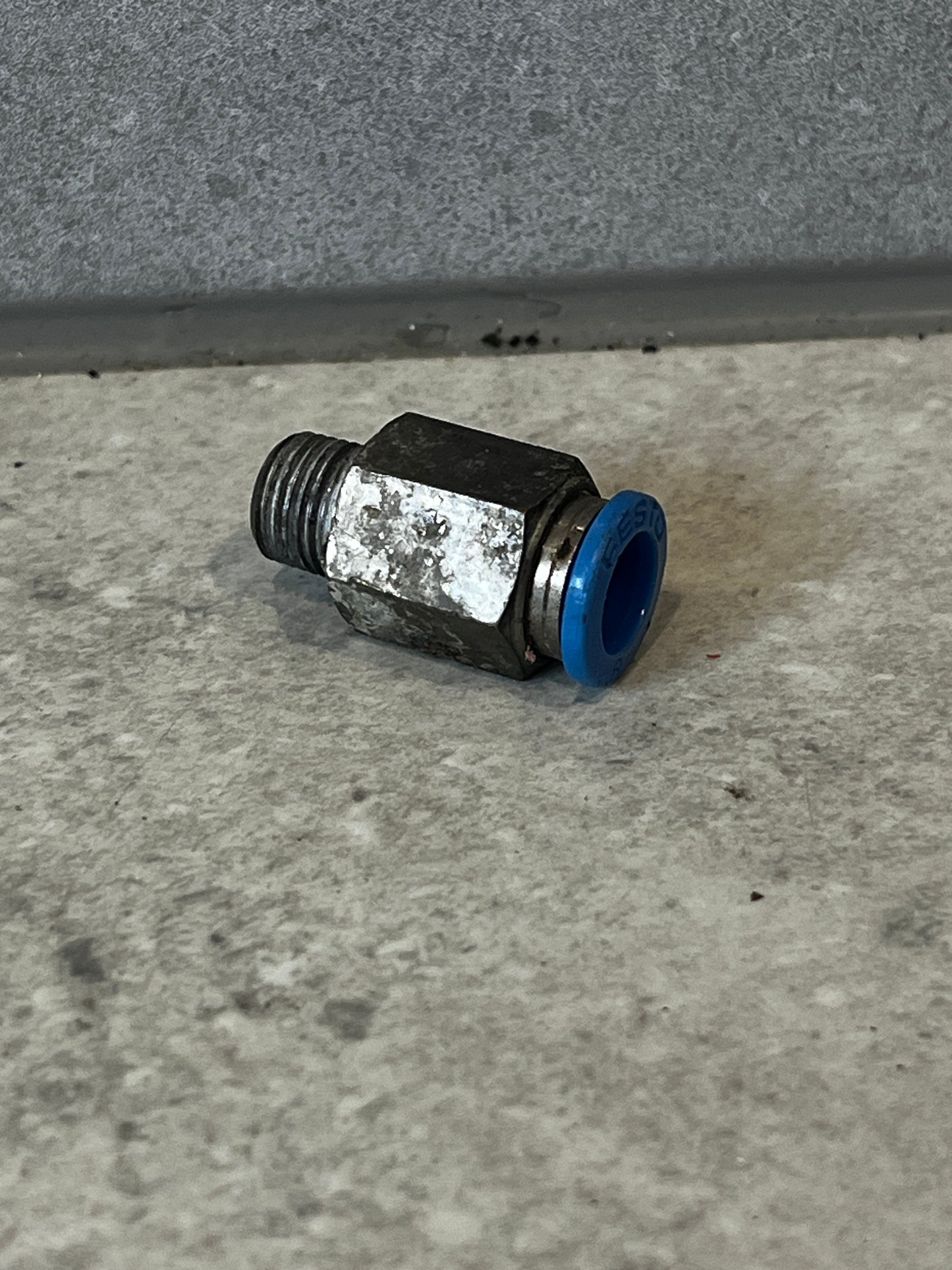 Festo pneumatic push-to-connect fitting with blue collar on concrete surface