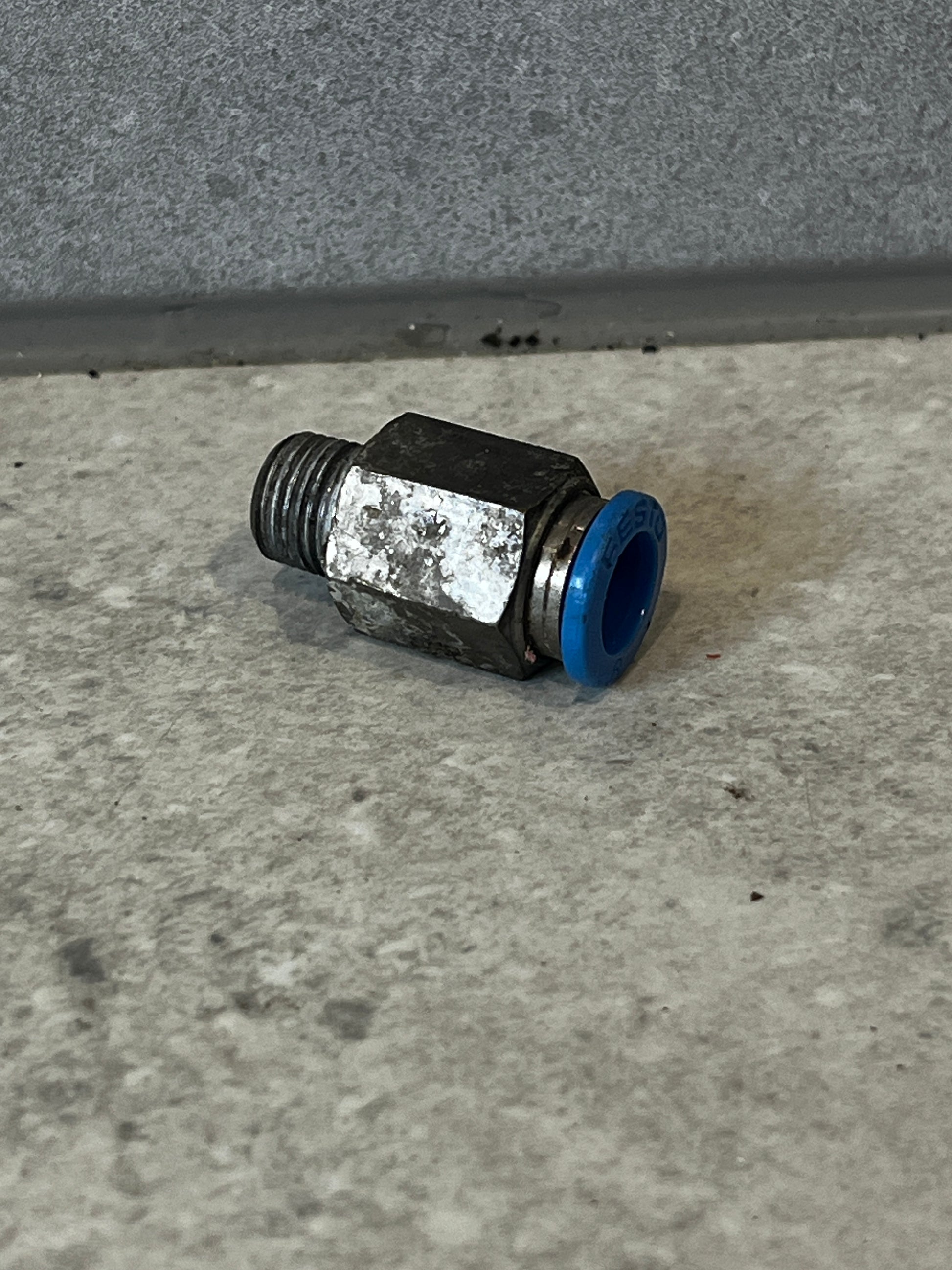 Festo pneumatic push-to-connect fitting with blue collar on concrete surface