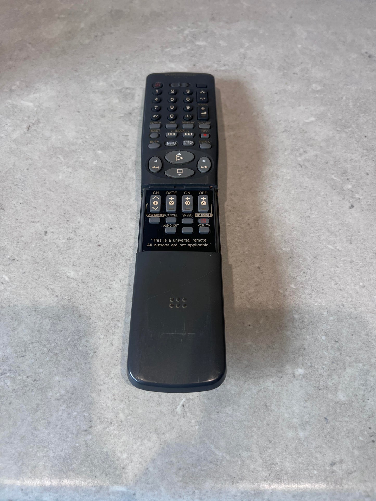 Universal remote control with sliding cover and multiple buttons on a countertop