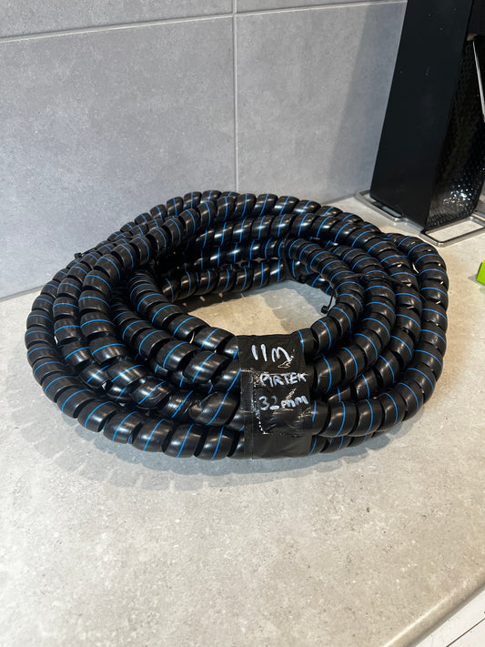 Coiled spiral hose protection wrap made of durable black material with blue stripes on a gray countertop