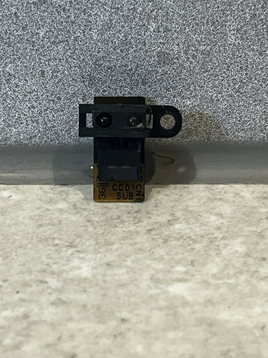 Close-up of a small black infrared camera module with a flexible circuit board for laptops
